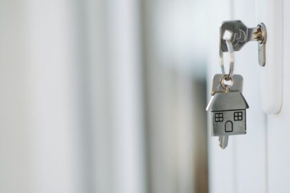 Cheie cu breloc în formă de casă, lăsată în ușa unei locuințe