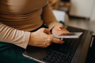 Settled status în 2026: o femeie își verifică statutul EUSS pe telefon, lângă laptop