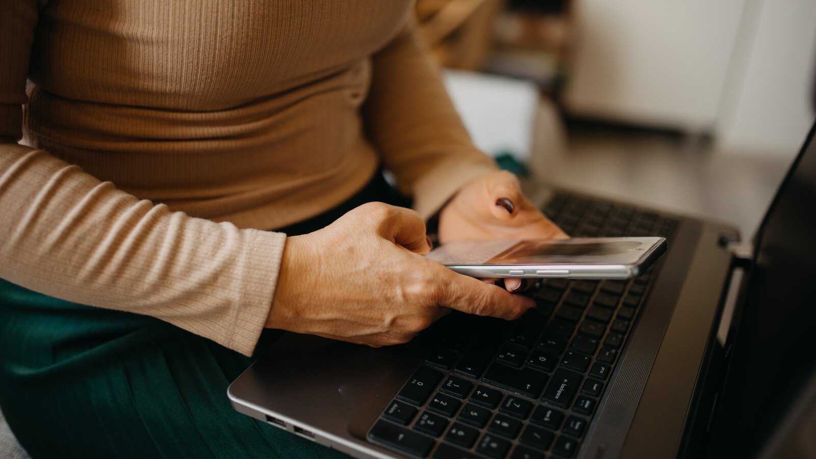 Settled status în 2026: o femeie își verifică statutul EUSS pe telefon, lângă laptop