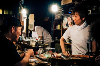 Angajat la tejgheaua unui restaurant care servește un client seara, imagine pentru ghidul despre hărțuirea la muncă de către clienți în UK