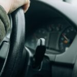 Șofer cu mâna pe volan, în interiorul unei mașini