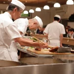 Bucătari la lucru în bucătăria unui restaurant, imagine pentru salariul minim în UK 2026