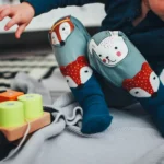 Copil mic care se joacă pe covor cu jucării de lemn, imagine pentru Tax-Free Childcare în UK