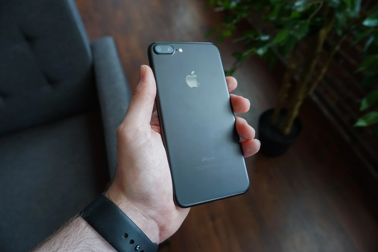 Mână care ține un telefon mobil negru, cu care poți cere un tax refund din aplicația HMRC